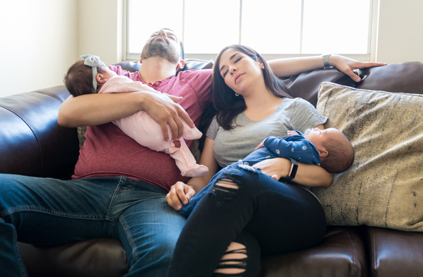 Tired mom and dad each holding a baby it their arms